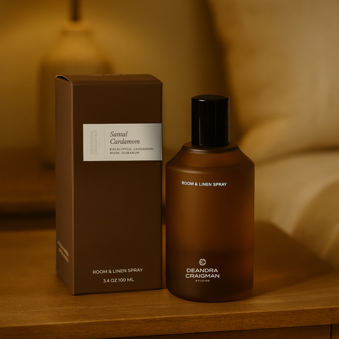 Room spray bottle and packaging on a wooden surface with a warm, blurred background