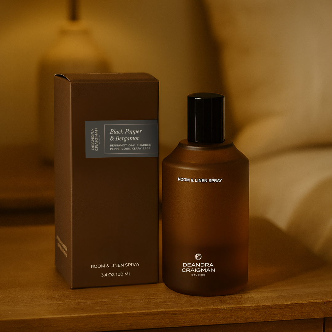 Room spray bottle and packaging on a wooden surface with a warm, blurred background
