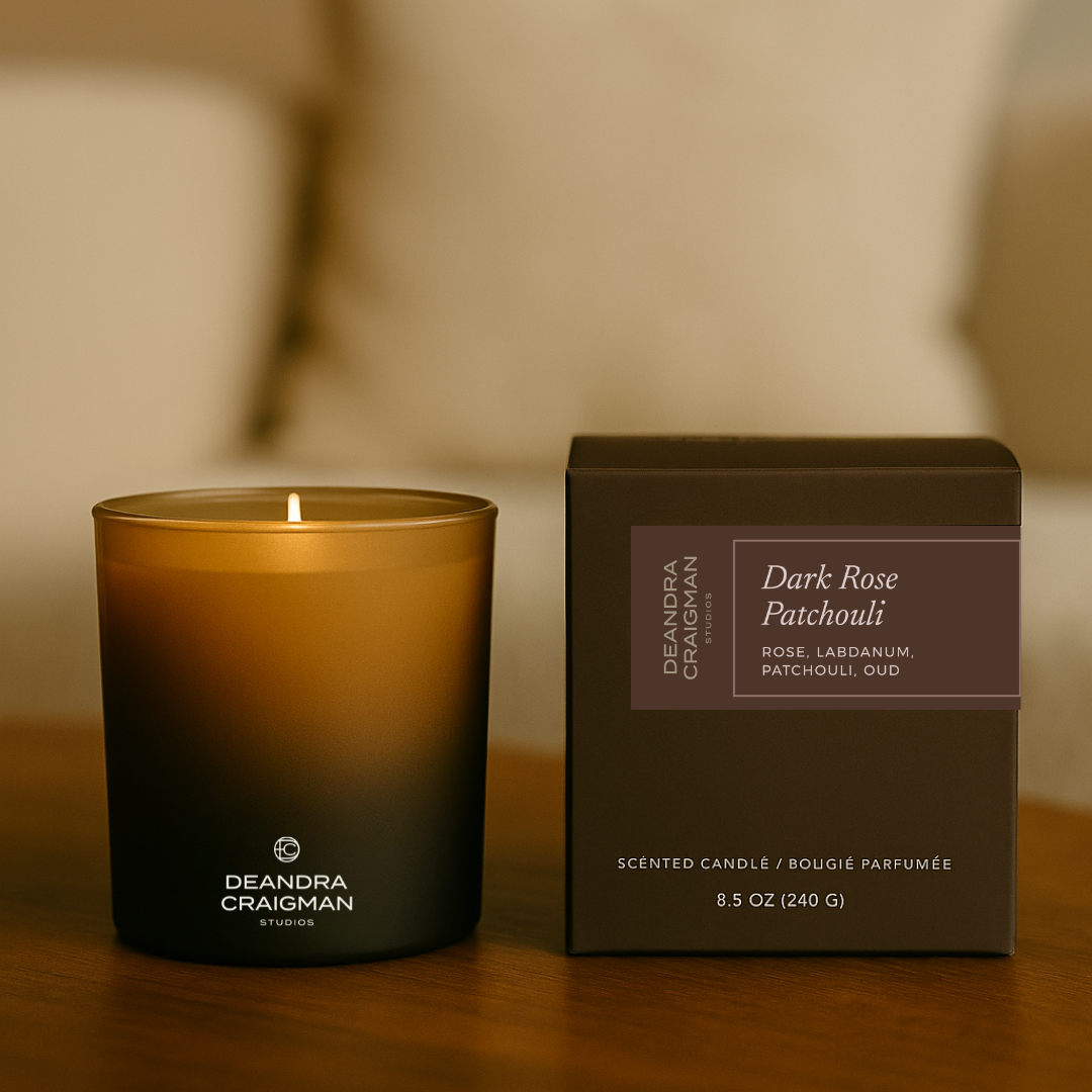 Scented candle and its packaging on a wooden surface with a blurred background